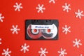 Audio cassette tape with decorative snowflakes on a red background. Music for Christmas mood.