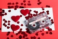 Audio cassette tape on red background with fabric heart