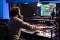 Audio expert operating on control desk with motorized faders and mixing console