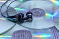 Audio headphones on a pile of glossy compact discs or cd`s with colored light reflections Royalty Free Stock Photo