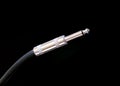 Audio instrumental cable with silver jack isolated on black background closeup
