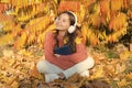 Audio library. Small girl listen to audio book in headphones. Cute kid in stereo earphones sit on autumn leaves. Little