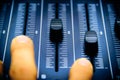 Audio mixer, mixing desk controls and fader, music mixing console with the hand of the technician moving the faders. Degraded Royalty Free Stock Photo