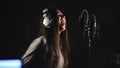 Audio recording studio. Woman with headphones and studio microphone singing. Royalty Free Stock Photo