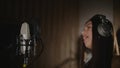 Audio recording studio. Woman with headphones and studio microphone singing. Royalty Free Stock Photo