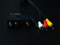 Audio-video adapter with plugs on dark background.