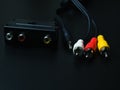 Audio-video adapter with plugs on dark background.