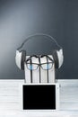 Audiobook on black board background. Headphones put over stack of colorful books, empty cover, copy space for ad text Royalty Free Stock Photo