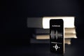 Audiobooks concept. Smartphone screen with audiobook application on paper books black background. Concept of education