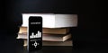 Audiobooks concept. Smartphone screen with audiobook application on paper books black background. Concept of education