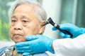 Audiologist or ENT doctor use otoscope checking ear of asian senior woman patient treating hearing loss problem