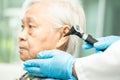 Audiologist or ENT doctor use otoscope checking ear of asian senior woman patient treating hearing loss problem