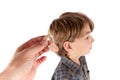 Audiologist`s hand holding a hearing aid in front of a young boy