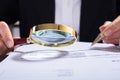 Auditor Inspecting Financial Documents At Desk