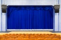 The auditorium in the theater. Blue curtain on the stage. Blue-brown chair. Room without people