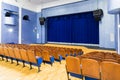 The auditorium in the theater. Blue curtain on the stage. Blue-brown chair. Room without people Royalty Free Stock Photo