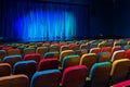 The auditorium in the theater. Blue-green curtain on the stage. Multicolored spectator chairs. Lighting equipment Royalty Free Stock Photo