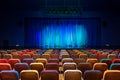 The auditorium in the theater. Blue-green curtain on the stage. Multicolored spectator chairs. Lighting equipment Royalty Free Stock Photo