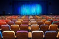 The auditorium in the theater. Blue-green curtain on the stage. Multicolored spectator chairs. Lighting equipment Royalty Free Stock Photo