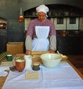 Victorian Kitchen maid making pastry in old kitchen using rolling pin.