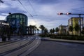 Audubon Aquarium with train tracks in the street and lush green palm trees along the riverfront with clouds at sunset