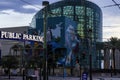 Audubon Aquarium with train tracks in the street and lush green palm trees along the riverfront with clouds at sunset