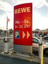 Red display at the entrance of the parking area of the REWE supermarket with opening days an