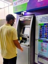 25 Aug 2020, Dhaka, Bangladesh. An asian male wearing mask using ATM machine for withdrawal of money