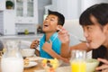 aughing asian brother sitting at breakfast table with sister eating Royalty Free Stock Photo