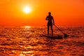 August 4, 2021. Anapa, Russia. Male athlete on paddle board at sea with sunset or sunrise. Man on Red Paddle sup board