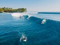 August 8, 2021. Bali, Indonesia. Aerial view with surfing on barrel wave. Blue glassy waves and surfers in ocean