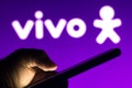 August 6, 2021, Brazil. In this photo illustration a silhouette of a hand holding a mobile phone is seen in front of Vivo logo