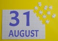 31 august calendar date on a white puzzle with separate details. Puzzle on a yellow background with a blue inscription