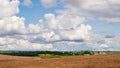 August landscape. Large cumulus clouds in the blue sky over a freshly mown field