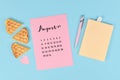 August month concept with pink calendar sheet, book, pen, paper heart and waffle pieces on blue background
