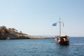 August 23rd 2019 - Sithonia, Greece - Rocky coast and tourist boat in Kelyfos islet, Neos Marmaras