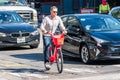 August 21, 2019 San Francisco / CA / USA - Man riding a Jump electric bike; on the right a car with the UBER sticker can be seen