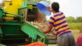 Tractor working with thresher machine in field. Farmers separating straw husk from grains Royalty Free Stock Photo