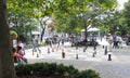 Older men play large street chess on the boulevard. Around a lot of spectators