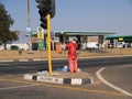 August 15 2007 in Soweto South Africa; African man in red standing in middle of road waiting for cars to stop to try and sell