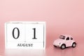 August 01st. Day 1 of month. Calendar cube on modern pink background with car