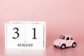 August 31st. Day 31 of month. Calendar cube on modern pink background with car