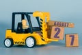 august 27th. Day 27 of month, Construction or warehouse calendar. Yellow toy forklift load wood cubes with date. Work planning and Royalty Free Stock Photo