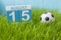 August 15th. Image of august 15 wooden color calendar on green grass lawn background with soccer ball. Summer day. Empty