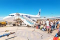 People stay in line boarding to an airplane of UTair airlines