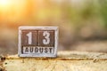 August 13 on a wooden calendar standing on stump forest with solar flare.