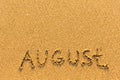 August - word inscription on the gold sand beach.