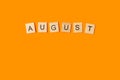 August word made with wooden letter blocks on an orange background