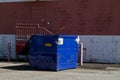 Blue dumpster behind a building shopping center
