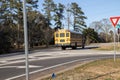 Yellow school bus drives down the road back view